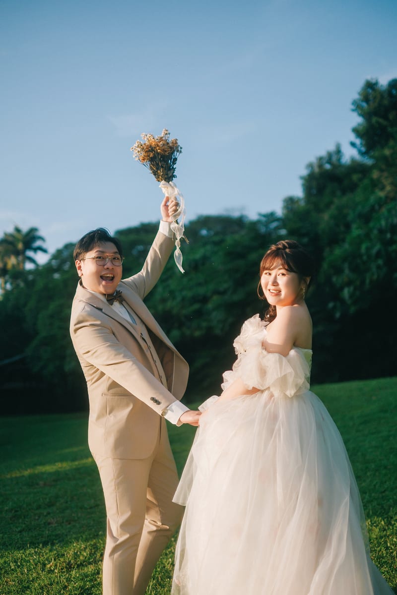建霖與娟娟在草地上舉起捧花歡呼